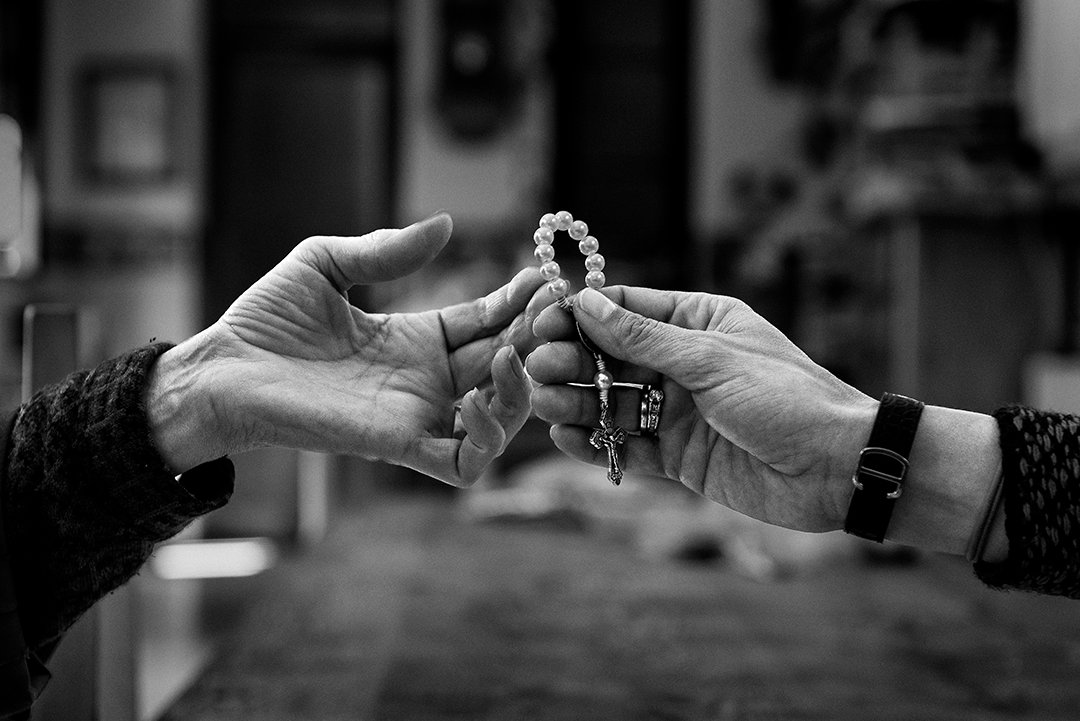 Two hands exchanging a rosary.